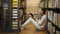 Girl chooses a book on a shelf in the library. Girl sitting on the floor in the library