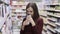 Girl chooses shower gel and sniffs it in cosmetics department at supermarket, emotion dislike