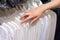 Girl chooses a white shirt in the store. Selection of new clothes close-up of hands. Shopping concept