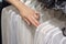 Girl chooses a white shirt in the store. Selection of new clothes close-up of hands. Shopping concept, business concept