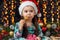 Girl in christmas decoration with gift, dark background with illumination and boke lights, winter holiday concept