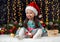 Girl in christmas decoration with gift, dark background with illumination and boke lights, winter holiday concept