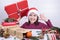 Girl in a christmas hat holding a gift and smiling cute and showing a boat