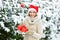 Girl with christmas tree decoration. lady red santa hat at fur tree. winter nature forest covered with white snow