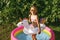 A girl with a circle in the shape of a unicorn having fun in a small inflatable swimming pool in the yard. Summer outdoor recreati