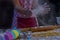 Girl claps hands and spraying flour over dough on dark background