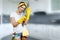 A girl, a cleaning woman before cleaning, is putting on her hands rubber, yellow gloves on a blurred background. The concept of