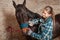 The girl cleans the horse from dust and dirt with a special brush