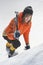 Girl climber climbs a snow cornice using ice axes through snow blown away by the strong wind.