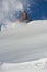 Girl climber climbs a snow cornice using ice axes through snow blown away by the strong wind.