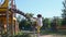 The girl climbs on the children`s playground in the early summer morning