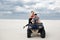 A girl climbs her boyfriend on a quad bike, they are preparing for a trip in the desert, a stylish young couple