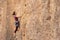 The girl climbs the rock. The climber is training to climb the rock. A strong athlete overcomes a difficult climbing route.