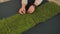 Girl with a clock on his hand staples pieces of artificial turf lying on the floor. Close-up of the girl`s hands.