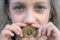 A girl close-up with green eyes holds a bitcoin coin in her mouth. Concept of easy bitcoin investing and trading