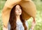 Girl with closed eyes in a big wicker hat outdoors in summer. Fashion and beauty. Meditation and relaxation Ñoncept