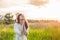 Girl closed her eyes, praying in a field during beautiful sunset. Hands folded in prayer concept for faith