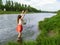 Girl in clothes splashing in Uzh river Uzhhorod, Ukraine - view from the back