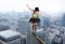 Girl clown walks on a rope over the skyscrapers of a city