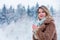 Girl in coat with cup of drink in a snow forest