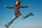 Girl in coat and jeans in jump against blue sky