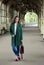 Girl in coat and jeans with red bag under the arches of the meta