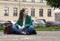 girl in coat sitting on the ground in the city on building background