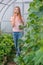 Girl collects cucumbers in the summer in a greenhouse