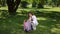 A girl collects trash scattered on the grass into a plastic bag while walking through a city park on a sunny summer day.