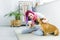 Girl with colorful hair holding cup of coffee, sitting on floor and petting cute bulldog