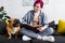 Girl with colorful hair sitting on sofa with book and petting cute bulldog