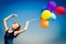 Girl with colour balloons at blue sky background.