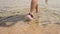 Girl comes into the sea in rubber shoes, close-up.