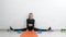 the girl conducts a home online stretching workout, sitting on a cross twine