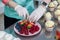 Girl confectioner cuts fresh berries with a knife to decorate the cake