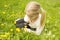 Girl considers dandelions flower through a magnifying glass