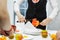 Girl cook in a black suit cuts out flesh from a grapefruit with a knife.