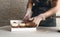 A girl cook in a gray apron packs cupcakes with cream in a gift box to send the order to the customer.