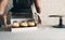 A girl cook in a gray apron packs cupcakes with cream in a gift box to send the order to the customer.