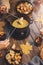 Girl cooks gourmet Swiss fondue dinner with cheese on fire, autumn wooden background with maple leaves. Top view, flat