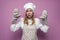 Girl cooks in uniform raises her hands and shows baking gloves on a colored background, a beautiful housewife in kitchen clothes