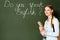 Girl with copybooks and backpack standing near chalkboard with do you speak English lettering