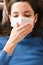 The girl coughs in a bandage. first signs of coronavirus. Girl in a white mask closes her mouth with her hand and coughs close-up