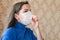 The girl coughs in a bandage. first signs of coronavirus. Girl in a white mask closes her mouth with her hand and coughs close-up