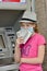 A girl counts money in a protective mask during a covid quarantine near an ATM