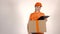 Girl courier in orange uniform delivering a big carton. Light gray backround, 4K studio shot
