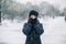 Girl covered mouth with gloves. The girl made a gesture, silence. A child walks after school on the street in a snowfall.