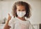 Girl with a covid face mask and thumbs up like sign showing she is wearing protection or caution against virus, One