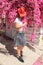 Girl in cowboy`s hat beside pink flowers