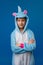A girl in a cozy blue unicorn kigurumi costume poses in the studio on a blue isolated background. Place for text